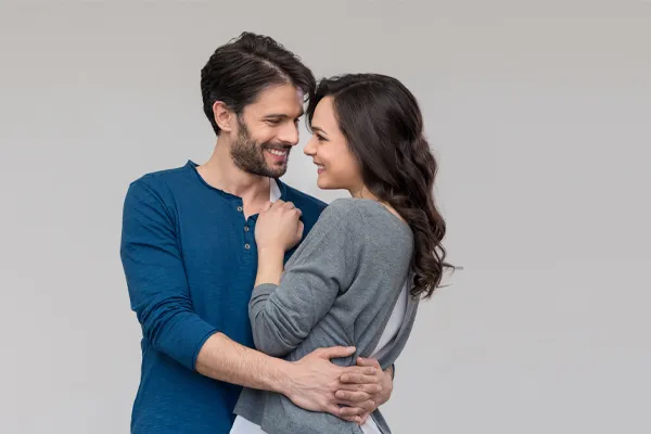 A man in a blue shirt embracing a woman in a gray shirt smiles due to his successful erectile dysfunction care from Tanya Zboril, NP of TBT Medical in Ottawa–Gatineau.