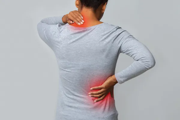 An image from behind of a woman suffering from Fibromyalgia holding her hands on her neck and lower back. Get fibromyalgia care from Tanya Zboril, NP of TBT Medical in Ottawa–Gatineau.