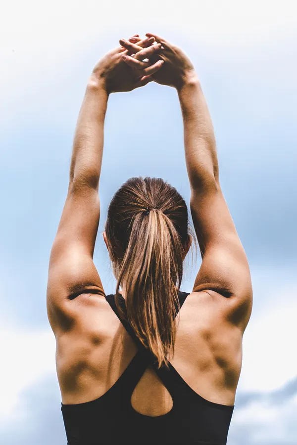 A toned woman seen from behind stretching her arms into the air. Get GLP-1 Weight Loss Injections from Tanya Zboril, NP of TBT Medical in Ottawa–Gatineau.
