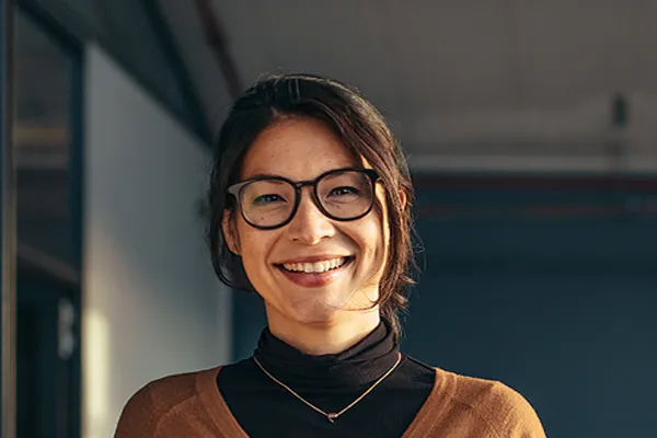 A brunette woman with glasses smiles in a gray-blue walled office. Get metabolic syndrome from Tanya Zboril, NP of TBT Medical in Ottawa–Gatineau.