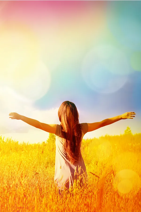 Ottawa-NAD-Therapy-Treatment Woman standing in a golden field with arms outstretched toward a vibrant, rainbow-hued sky, symbolizing vitality and inner renewal with NAD Therapy offered by Tanya Zboril, NP of TBT Medical in Ottawa–Gatineau.