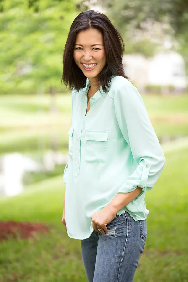 A middle-aged brunette woman in a light green button-up shirt stands outside smiling, happy with her perimenopause treatment from Tanya Zboril, NP of TBT Medical in Ottawa–Gatineau.