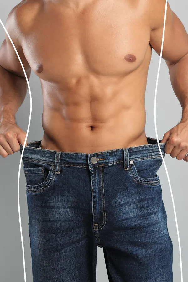 A strong shirtless man in jeans holds the waistlines of his too-big jeans to show the success of semaglutide weight loss from Tanya Zboril, NP of TBT Medical in Ottawa–Gatineau.