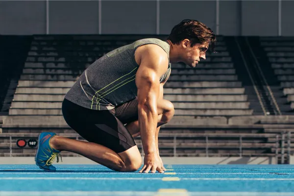 With a determined look, Aamuscular man in track clothes kneels at the start of a race. Get Sermorelin peptide therapy from Tanya Zboril, NP of TBT Medical in Ottawa–Gatineau.