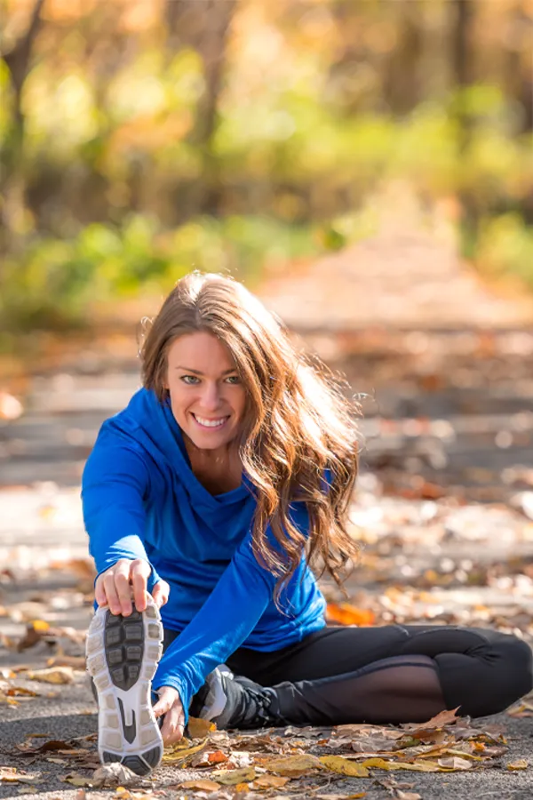 A healthy woman in blue sweats stretches on a trail before a run. Get Sermorelin peptide therapy from Tanya Zboril, NP of TBT Medical in Ottawa–Gatineau.