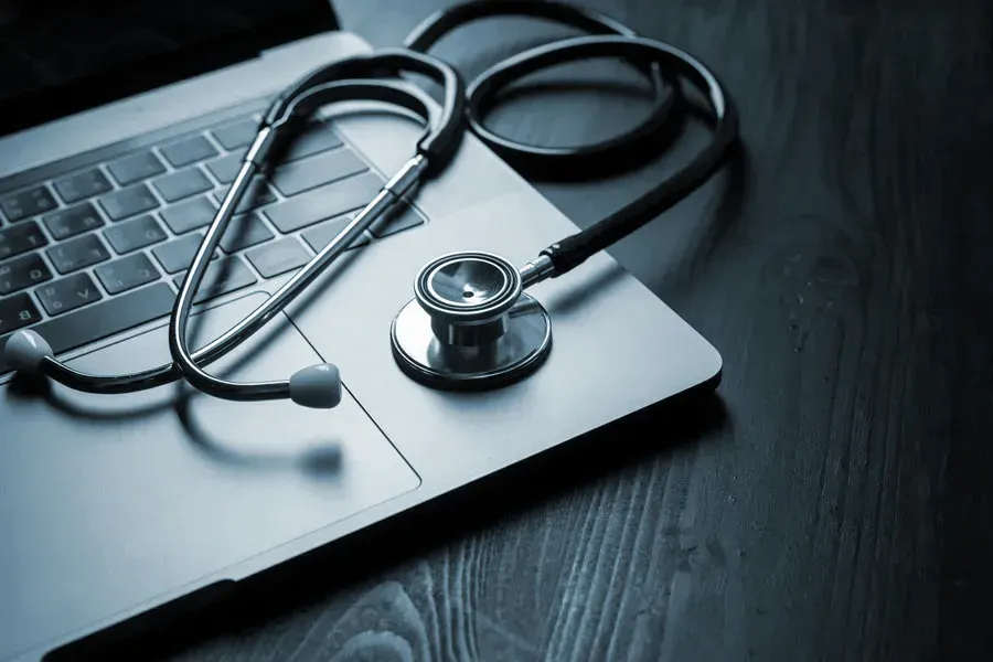 Telemedicine-Doctor An open laptop with a stethoscope lying on it on a wooden table, symbolizing telemedicine care from Tanya Zboril, NP of TBT Medical in Ottawa–Gatineau.