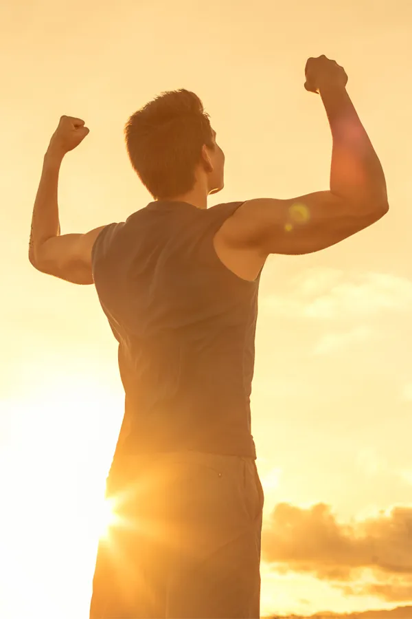 Wegovy-Weight-Loss-Treatment A motivational image of a young man standing with his back to the camera, arms raised triumphantly against a sunrise. Representing Wegovy Weight Loss Injections offered by Tanya Zboril, NP of TBT Medical in Ottawa–Gatineau.